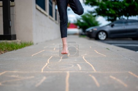 Selective focus on chalk numbers with a girl playing hop-scotch barefoot. High quality photo