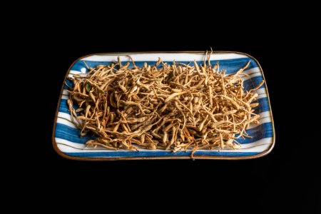 Téléchargez les photos : Japanese honeysuckle dried herbs - latin name Lonicera japonica - on a plate isolated on black - en image libre de droit