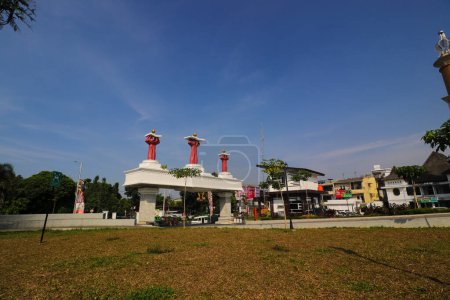 Téléchargez les photos : Sukabumi, Java occidental, Indonésie - 28 juillet 2022 : Monument Main tenant un livre avec fleur de lotus à la porte de la place de la ville de Sukabumi le matin avec un ciel bleu clair. - en image libre de droit