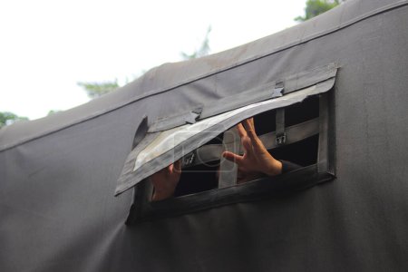 Foto de Mano tratar de abrir la cortina de un camión del ejército indonesio. - Imagen libre de derechos