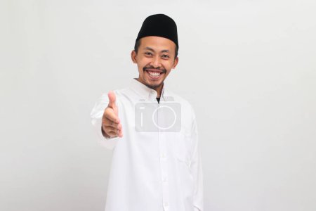 Téléchargez les photos : Un jeune Indonésien confiant, portant une chanson, un peci ou une kopiah, est prêt à serrer la main, isolé sur un fond blanc - en image libre de droit