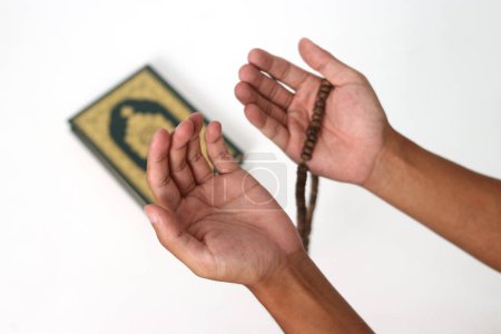 Großaufnahme von Händen, die im Gebet Palmen öffnen, nachdem sie während des Ramadan den Koran auf weißem Hintergrund rezitieren