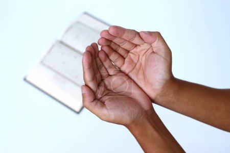Primer plano de las manos abriendo las palmas en oración después de recitar el Corán durante el Ramadán sobre un fondo blanco