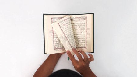 Un musulmán indonesio sosteniendo el libro sagrado del Corán sobre un fondo blanco