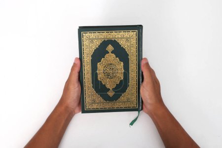 Téléchargez les photos : Un musulman indonésien tenant le saint livre du Coran sur fond blanc - en image libre de droit