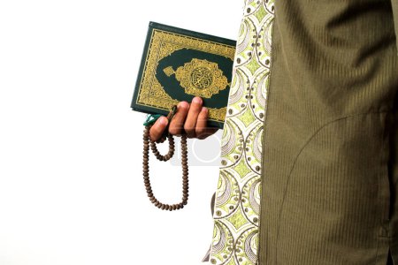 Photo for An Indonesian Muslim man holding the Holy Quran and tasbih on a white background prepares to perform Itikaf at a mosque during the last ten days of Ramadan, seeking spiritual reflection and renewal - Royalty Free Image
