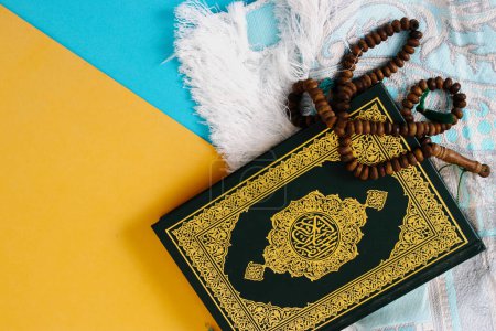 Der Heilige Koran mit Gebetsmatte und Tasbih auf blauem und gelbem Hintergrund