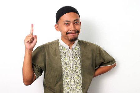 Photo for Excited Indonesian Muslim man in koko shirt and peci has an idea, raising his finger in a eureka moment. Isolated on a White background - Royalty Free Image