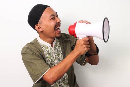 L'homme musulman indonésien excité à Koko et peci crie dans un mégaphone, annonçant des ventes de Ramadan et des offres spéciales. Isolé sur fond blanc