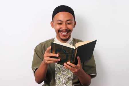 Un musulmán indonesio recitando el Sagrado Corán con enfoque durante el Ramadán. Aislado sobre un fondo blanco