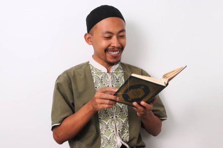 Un homme musulman indonésien récitant le Saint Coran avec une attention particulière pendant le Ramadan. Isolé sur fond blanc