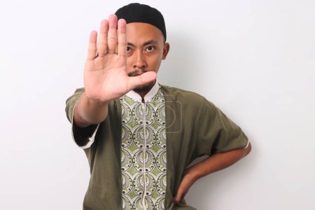 Un musulman indonésien à Koko et peci fait un geste d'arrêt, démontrant son engagement à éviter les interdictions pendant le mois sacré du Ramadan. Isolé sur fond blanc