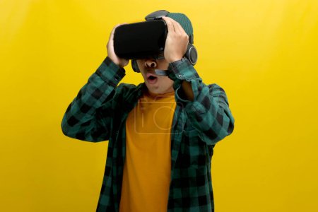 Erstaunte asiatische Mann mit einem VR-Headset sieht ein fesselndes 3D-Erlebnis. Vereinzelt auf gelbem Hintergrund.