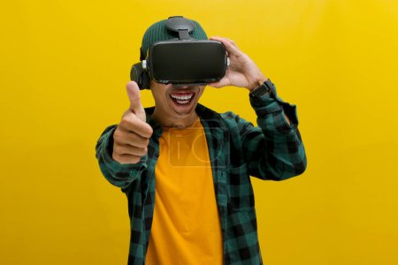 Glücklicher asiatischer Mann mit VR-Headset hebt den Daumen und genießt sichtlich seine Virtual-Reality-Erfahrung. Empfohlen VR-Konzept. Vereinzelt auf gelbem Hintergrund