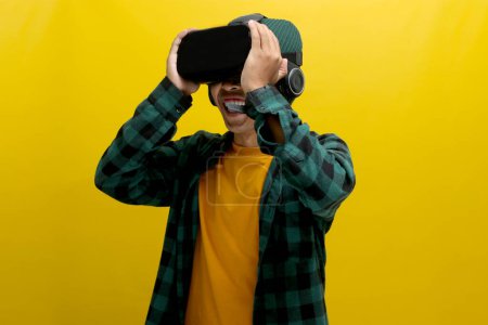 Erstaunte asiatische Mann mit einem VR-Headset sieht ein fesselndes 3D-Erlebnis. Vereinzelt auf gelbem Hintergrund.
