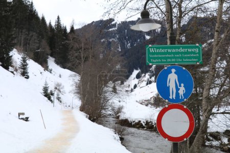 Foto de Sendero peinado a lo largo del río con el cartel que dice "sendero de invierno entre Vorderlanersbach y Lanersbach diariamente iluminado hasta la medianoche" - Imagen libre de derechos
