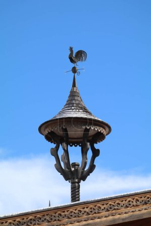 Photo for Traditional sculpted wooden tirolean bell tower on the roof of a farm house with blue sky in the background - Royalty Free Image