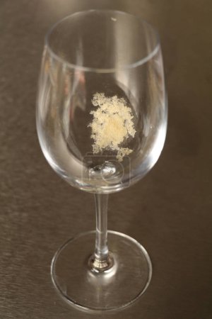 Téléchargez les photos : Cristaux de tartrate de vin blanc collés à l'intérieur d'un verre à vin vide - en image libre de droit