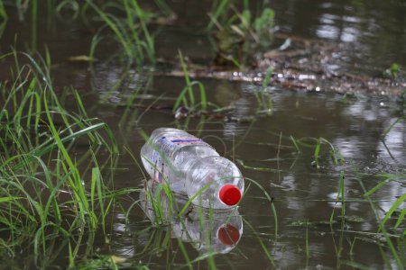 Foto de Botella de plástico desechada de un solo uso flotando en el agua - Imagen libre de derechos