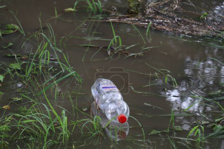 Téléchargez les photos : Bouteille en plastique jetée à usage unique flottant dans l'eau - en image libre de droit