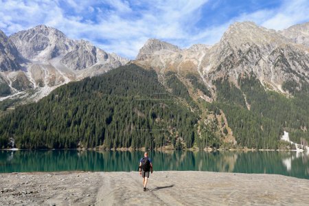 Téléchargez les photos : Randonneur en marchant vers un lac de montagne vert émeraude entouré de hautes montagnes alpines - en image libre de droit