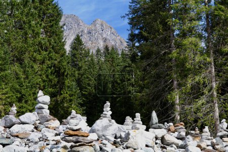 group of stone cairns by a coniferous forest with bare mountains in the background
