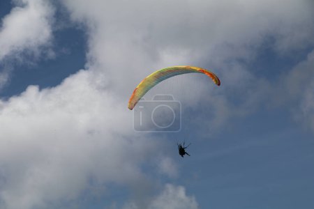parapente avec parachute coloré dans l'air avec une toile de fond de ciel bleu et nuages blancs