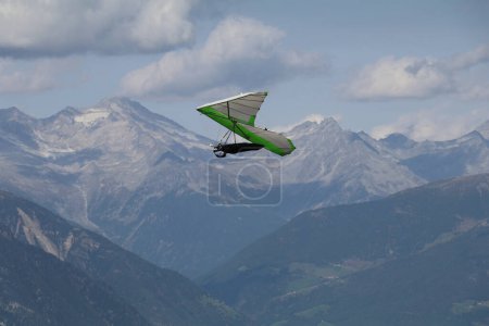 hang glider in the air with a backdrop of a blue mountain ridge