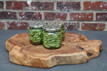 glass jars with wild garlic flowers in vinegar sitting on a wooden board