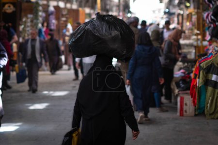 Téléchargez les photos : Arabic woman carries bag on head on street market - en image libre de droit