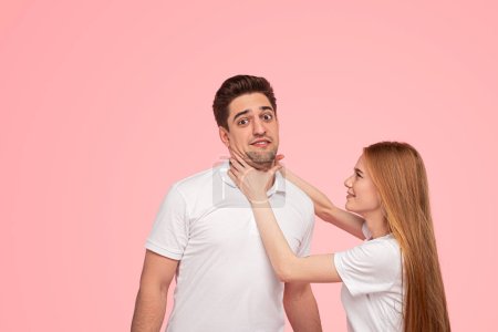 Téléchargez les photos : Agressif jeune femelle avec de longs cheveux roux essayant d'étrangler petit ami pendant la querelle sur fond rose - en image libre de droit