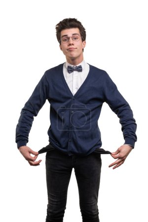Photo for Sad young male student with no money looking at camera and demonstrating empty pockets against white background - Royalty Free Image