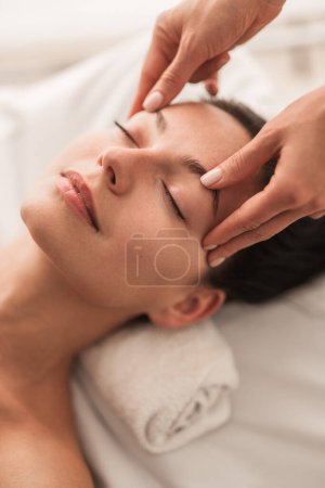 Photo for From above calm female closing eyes and enjoying face massage during session in spa salon - Royalty Free Image
