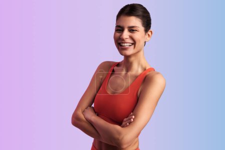 Photo for Positive young female in sportswear smiling and looking at camera while standing against gradient background - Royalty Free Image
