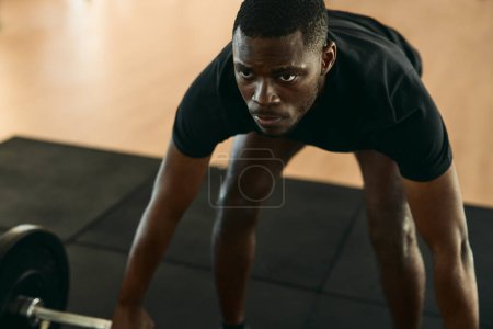 Téléchargez les photos : Haut angle foyer doux de l'athlète masculin afro-américain forte levant haltère lourde tout en faisant de l'exercice à la salle de gym pompage biceps - en image libre de droit