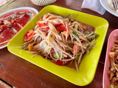 Téléchargez les photos : Salade de papaye épicée au crabe salé et poisson fermenté, croûte de porc, cuisine locale thaïlandaise de rue. - en image libre de droit