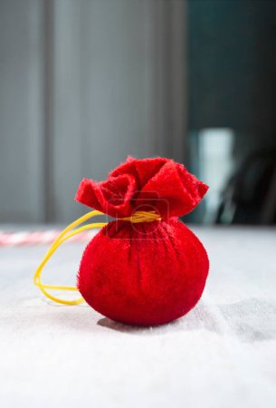 Photo for A red bag of gifts for Christmas and New Year is a toy. a small bag of dollars for the holidays. Santa Claus bag in miniature. A Christmas tree toy is a bag of textile gifts. - Royalty Free Image