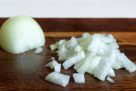 Photo for Chopped onions on a wooden board. Chopped onions on the table. On a wooden board, half an onion and a second, chopped half. - Royalty Free Image
