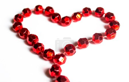 Téléchargez les photos : A heart is lined with beads on the table. The heart is lined with red beads on a wooden table. Valentine's Day - valentine on the table with your own hands. - en image libre de droit