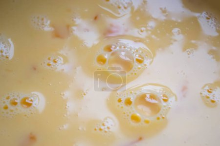 Liquid omelette. Mixed eggs with milk. Bubbles on a liquid omelet.