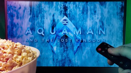 Photo for Kyiv. Ukraine. 10.11.2023: Person watching Aquaman and the Lost Kingdom movie on TV with popcorn and remote control. Stock editorial photo. - Royalty Free Image