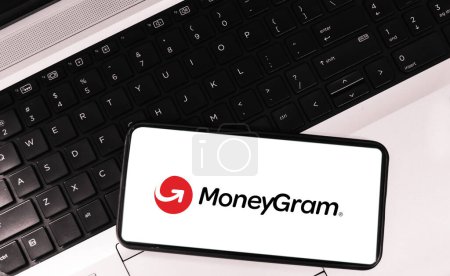 Foto de Financial Service company on mobile with laptop in the background. Moneygram mobile app concept editorial backdrop - Imagen libre de derechos
