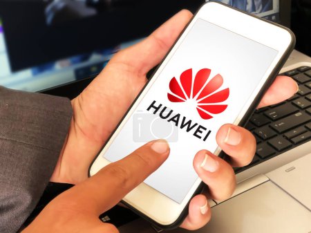 Foto de Hombre usando Huawei en la pantalla móvil tocando y portátil en el telón de fondo, editorial de la compañía móvil - Imagen libre de derechos