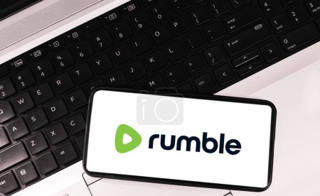 Photo for Modern trendy video streaming platform rumble on mobile screen with laptop in the backdrop, editorial - Royalty Free Image