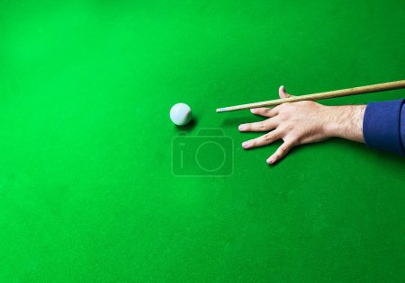 Téléchargez les photos : Homme frappant boule blanche sur la table de billard avec fond vert et espace de copie vide. Arrière-plan de table Snooker - en image libre de droit