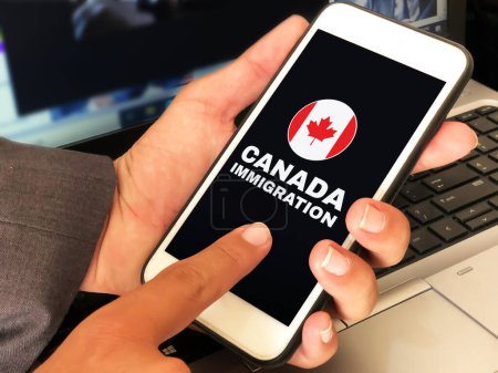 Foto de Aplicar para Canadá Fondo concepto de inmigración con el hombre tocando en la pantalla. Persona que toca la pantalla móvil y solicita inmigración - Imagen libre de derechos