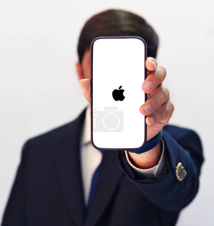 Foto de Hombre usando el teléfono móvil con Apple en la pantalla negra, telón de fondo del concepto de noticias editorial de tecnología. Monopolio de Apple en el concepto de mercado - Imagen libre de derechos