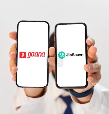Photo for Gaana Vs JioSaavan music listening app comparison to find out best, shown on two different smartphone screens editorial backdrop - Royalty Free Image