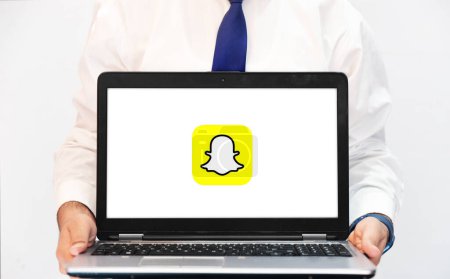Foto de Snapchat Concepto de versión web con pantalla portátil en poder de la persona en el espacio en blanco, fondo editorial - Imagen libre de derechos