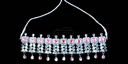 Schöne traditionelle Halskette in glänzender silberner Farbe mit rosa Juwelen darin auf isoliertem schwarzem Hintergrund.